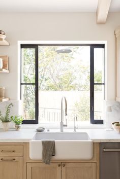 a white kitchen sink sitting under a window next to a dishwasher and oven