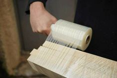 a person holding a roll of tape over some wood