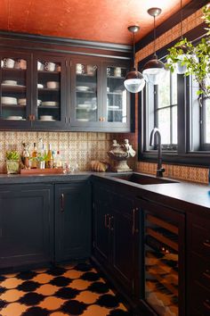 a kitchen with black cabinets and checkered flooring on the walls, along with potted plants