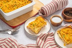 two plates with casserole on them next to a bowl of black beans and a wooden spoon