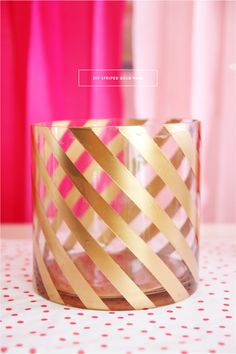 a pink and gold vase sitting on top of a polka dot tablecloth covered table