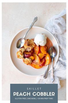 a white plate topped with fruit covered in ice cream next to two silver spoons