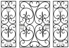 two wrought iron wall panels with candle holders on each side, one holding a lit candle