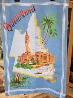 a tea towel hanging on a rack in a store with the map of queensland printed on it