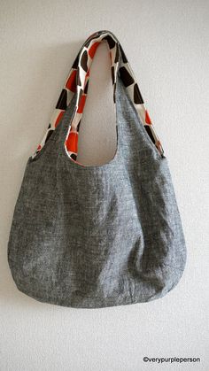 a gray bag hanging on the wall with an orange and black pattern around it's handles