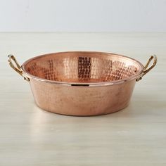 a large copper pan with handles on a table