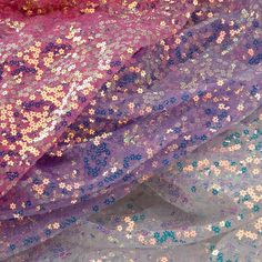 purple and blue sequin fabric with small flowers on the top, as well as other material