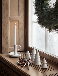 a white candle sitting on top of a wooden table next to a wreath and other decorations