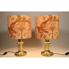 two lamps that have been turned on and are next to each other with the same fabric shade