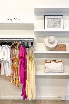 an open closet with clothes and hats hanging on shelvings in front of a white wall