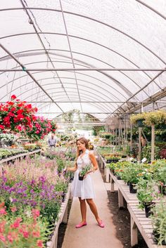 a woman standing in a greenhouse holding flowers