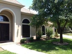 a house that has a tree in front of it and some grass on the ground