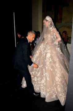 a man walking next to a woman in a wedding dress