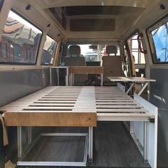 the inside of a van with a bed and table in it's center area