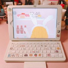 an open laptop computer sitting on top of a pink table next to bottles and cups