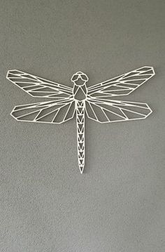 a white dragonfly is hanging on the wall