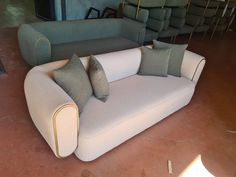 a couch with two pillows on it in a room filled with chairs and other furniture