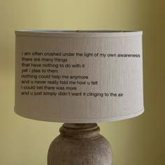 a lamp with a poem on it sitting in front of a yellow wall and the words i am often confused under the light of my own awareness