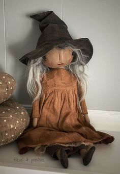 a doll sitting on top of a shelf next to pillows