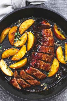 pork chops and peaches in a skillet on top of a gray table