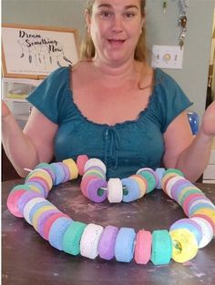 a woman standing in front of a cake decorated with multicolored doughnuts