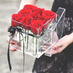 a person holding a clear box with red roses in it