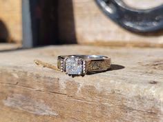 an antique style ring sits on top of a piece of wood