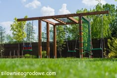 a wooden swing set in the middle of a green yard