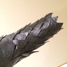 a close up of a black umbrella on a white table with a wall in the background