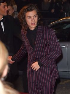 a man in a suit is walking down the red carpet with his hand on his hip