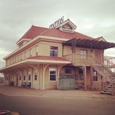 an old yellow building with a sign on top and stairs leading up to the second floor