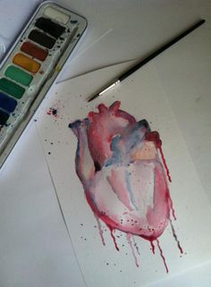 a drawing of a heart on paper next to a paintbrush and watercolor palette