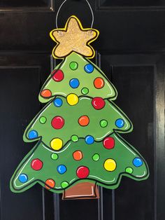 a christmas tree shaped door hanger hanging on a black door with polka dots and a star