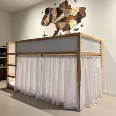 a bunk bed with white curtains and a map on the wall