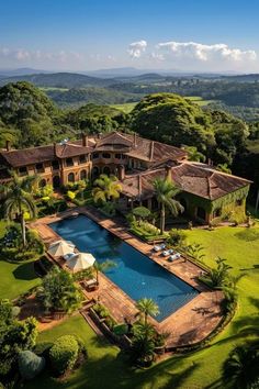 an aerial view of a large house with a pool in the yard and lush greenery surrounding it