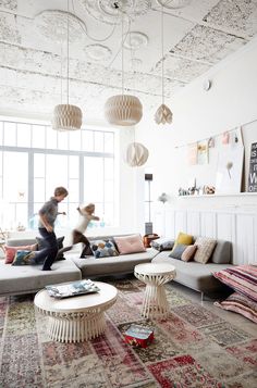 two people are running through a living room with couches and rugs on the floor