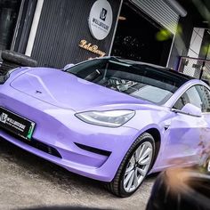 a purple electric car parked in front of a building