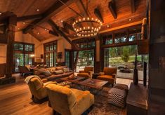 a living room filled with lots of furniture next to large windows and wooden flooring