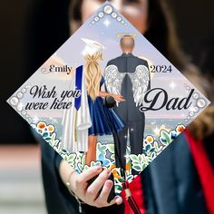 a woman holding up a graduation cap with an image of a man and woman on it