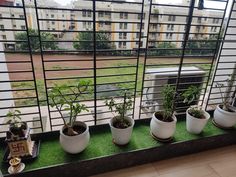 several potted plants sit on a window sill in front of an open air conditioner