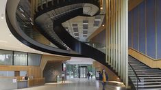 two people are walking up and down the stairs in an office building with spiral staircases