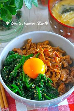 a bowl filled with meat and vegetables next to chopsticks