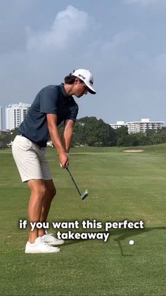 a man hitting a golf ball with his club on the green in front of a cityscape