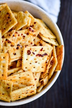 a white bowl filled with crackers on top of a wooden table