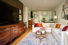 a living room filled with furniture and a flat screen tv on top of a wooden dresser