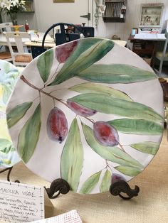 a plate with fruit painted on it sitting on top of a table in a store