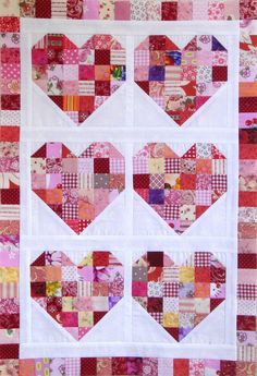 a quilted wall hanging with hearts on it