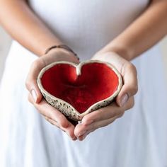 a woman holding a red heart in her hands