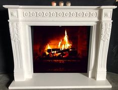 a white fireplace with lit candles in it