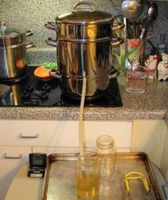 there is a pot on the stove with water coming out of it and some glasses sitting next to it